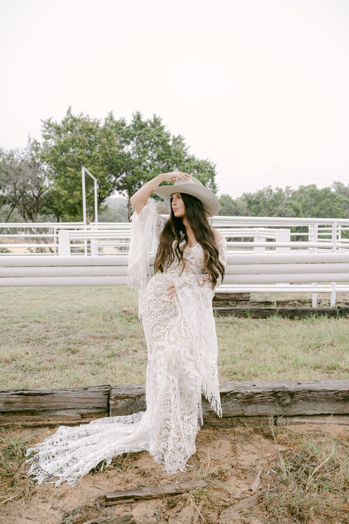 Bride lifting hat while posing in The Videre’s arena in lace fringe gown
