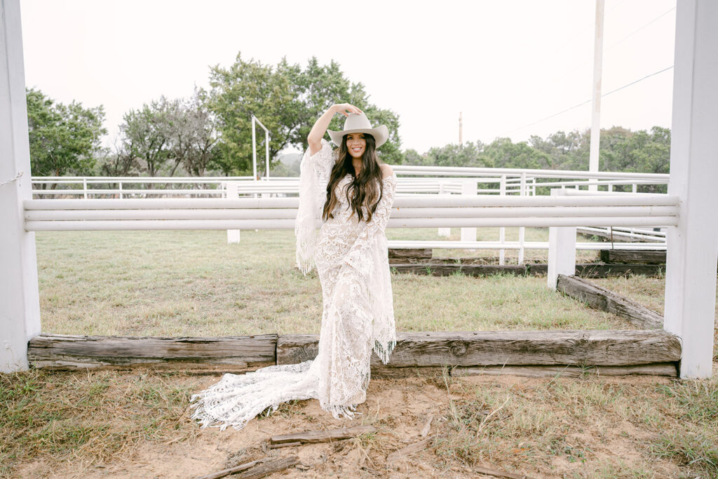 Bride playfully tipping hat in open field arena at The Videre wedding venue