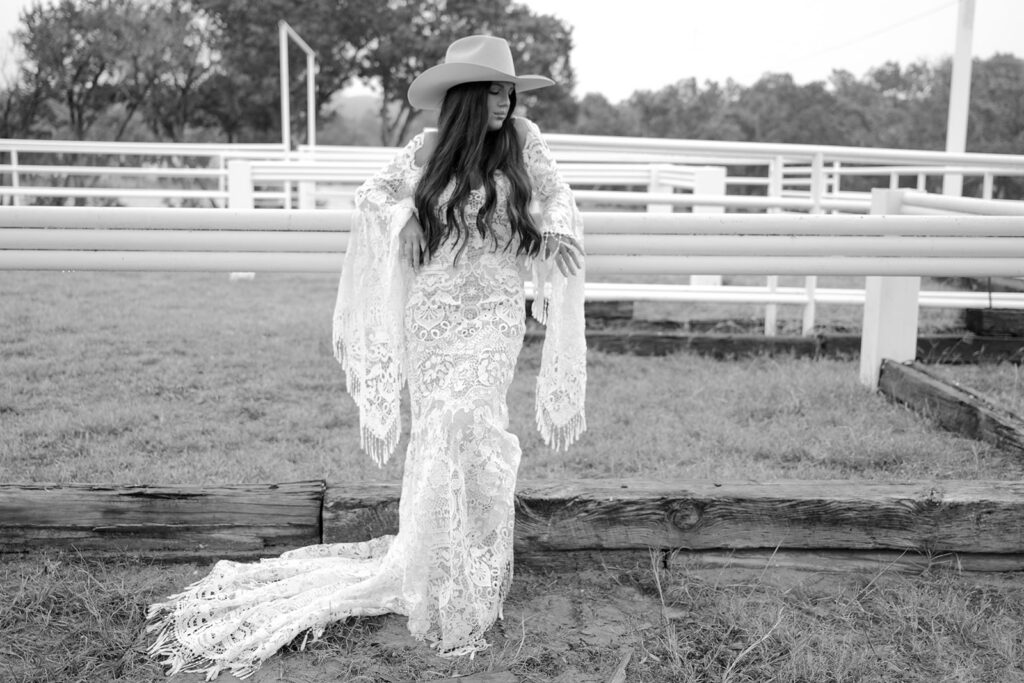 Bride in lace gown and wide-brim hat at The Videre wedding venue’s open-air arena, black and white photo