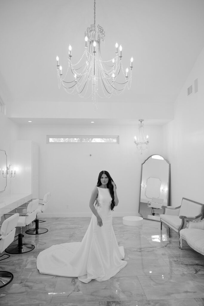 Bride standing with long train inside chandelier-lit room at The Château, The Videre wedding venue