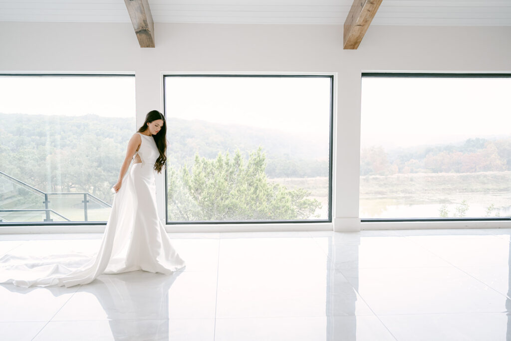 Bride inside The Videre wedding venue standing in front of panoramic hill country views and floor-to-ceiling windows.