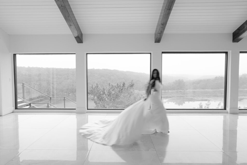 Bride twirling inside The Videre wedding venue with soft motion blur and panoramic windows