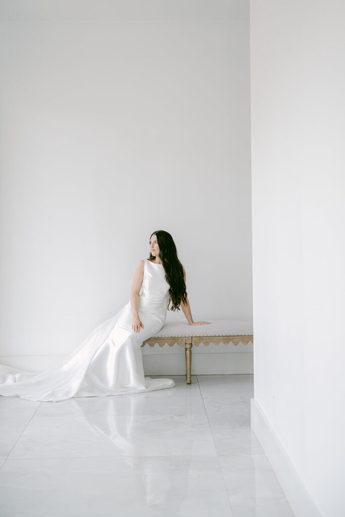 Bride seated in an all-white room with a long train flowing beside her at The Videre wedding venue