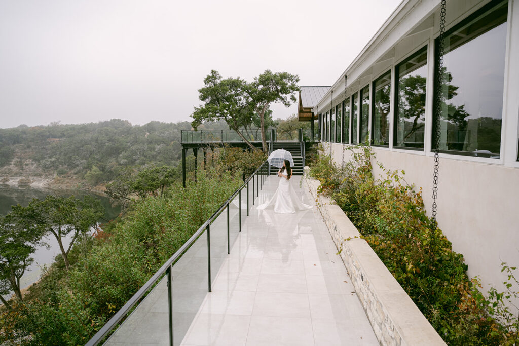 Bride walking away down polished stone terrace walkway at The Videre with tree framing the scene