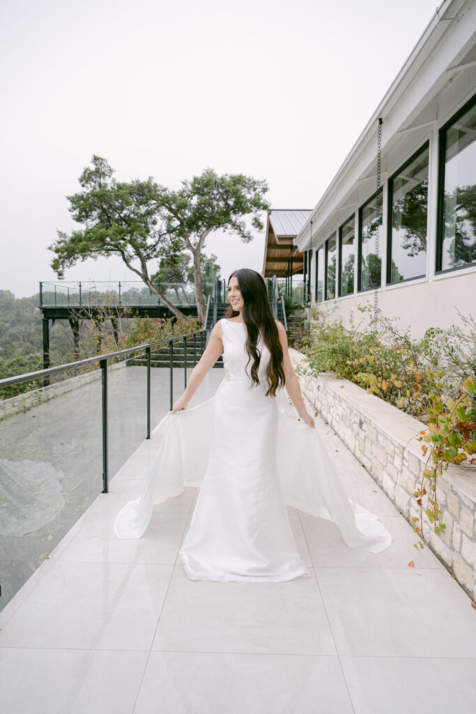 Bride on balcony at The Videre wedding venue looking toward ceremony site and Texas hill country