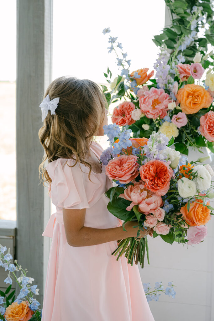 Young flower girl holding oversized wedding bouquet at The Allen Farmhaus ceremony