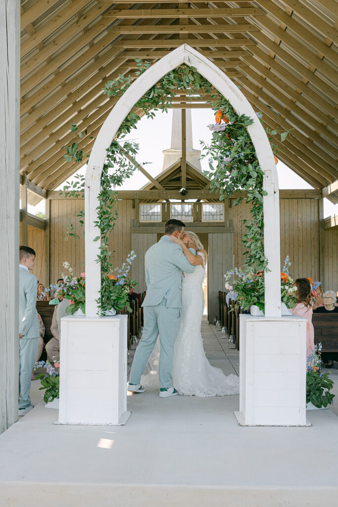 Bride and groom sharing their first kiss inside chapel-style altar at The Allen Farmhaus in New Braunfels