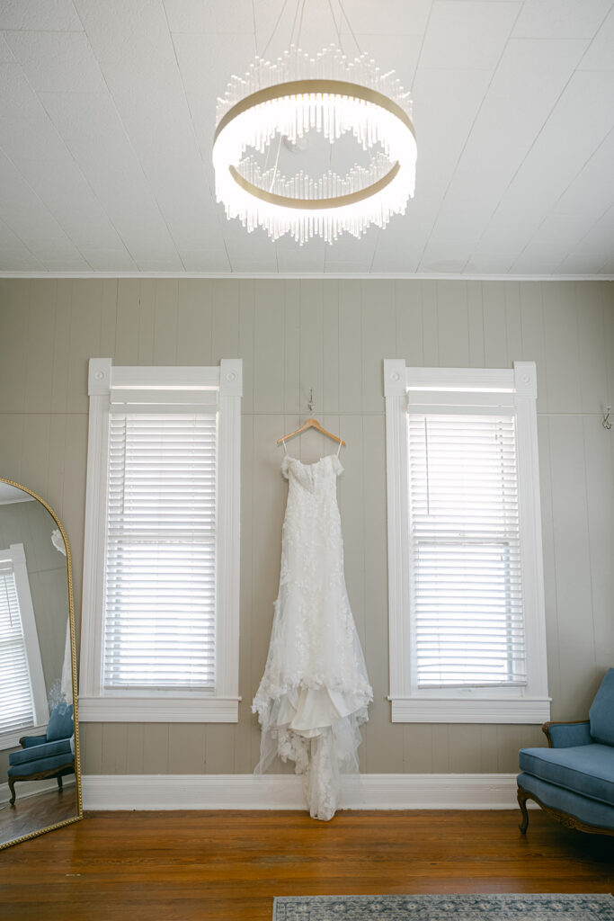 Bridal gown hanging in bridal suite with light filtering through windows at The Allen Farmhaus