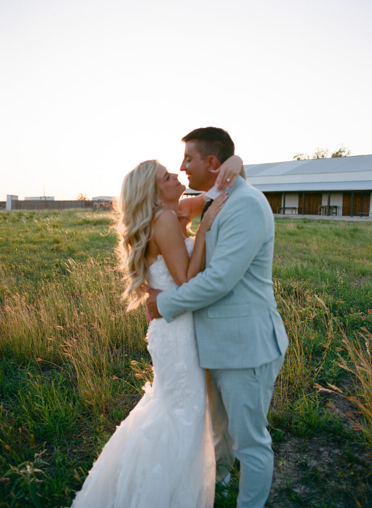 Bride and groom embracing at golden hour in open field at The Allen Farmhaus, photographed on film
