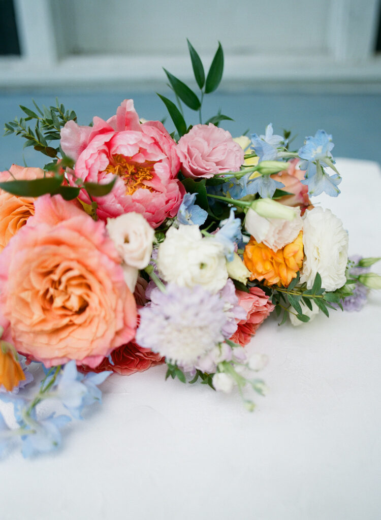 Bridal bouquet photographed on 120 film with vibrant coral, peach, and lavender flowers